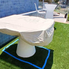 A mushroom-shaped table is near a Kettler FAS Ciclope White Outdoor Foosball Table on turf and blue tiles.