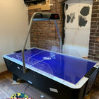 Dynamo 8' Pro Style Home Air Hockey Table with cracked surface, blue, in brick-walled room.