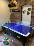 Dynamo 8' Pro Style Home Air Hockey Table with cracked surface, blue, in brick-walled room.
