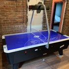 Dynamo 8' Pro Style Home Air Hockey Table with electronic scorekeeper in brick-walled room.