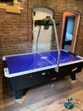 Dynamo 8' Pro Style Home Air Hockey Table with electronic scorekeeper in brick-walled room.