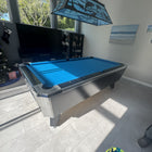 Pool table with blue felt in a room with a television and lamp.