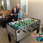 A group stands next to a Tornado Tournament Competition T-3000 Foosball Table in Silver.