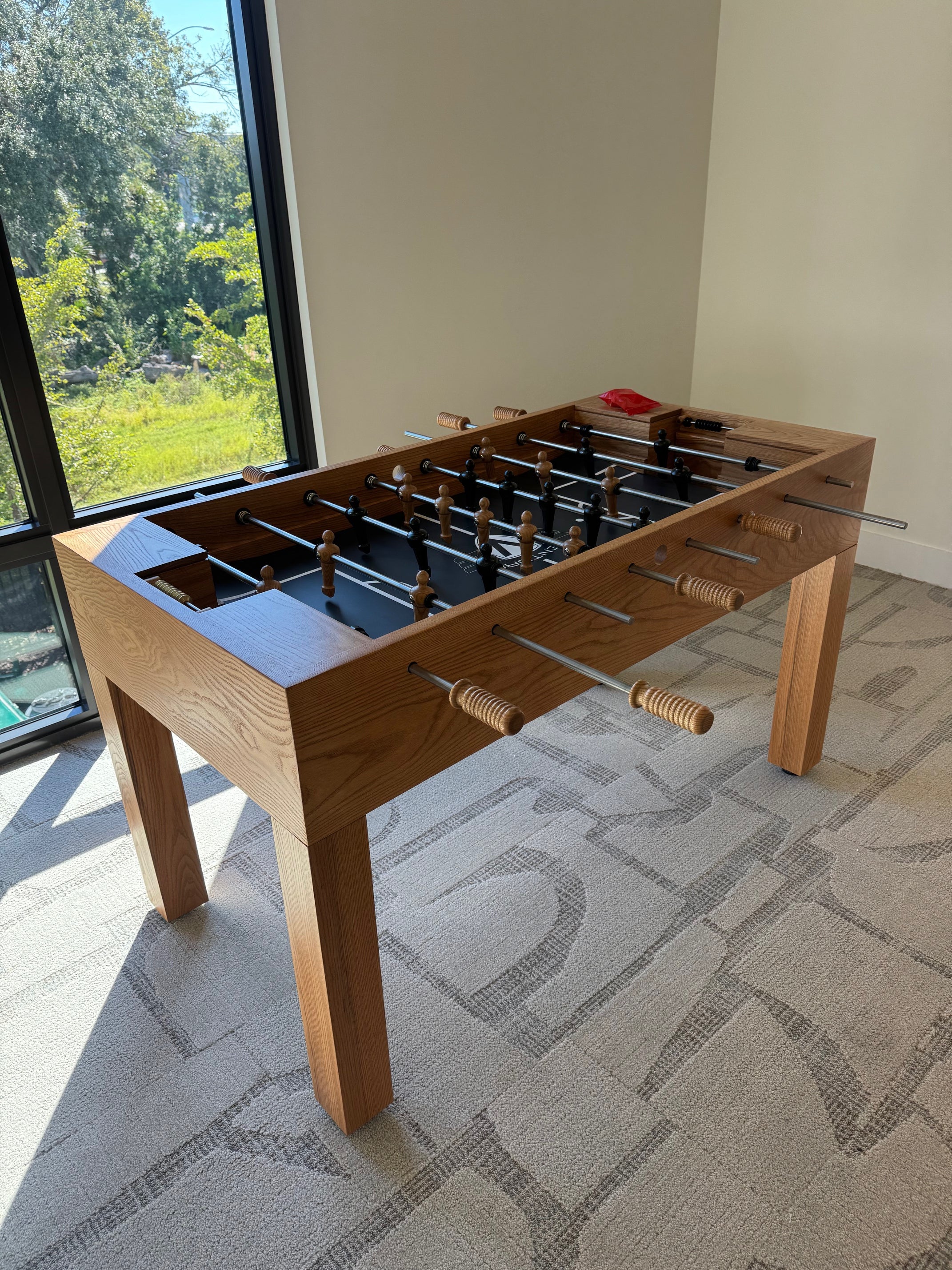 Venture Wooden foosball table in a room with a window and carpeted floor.