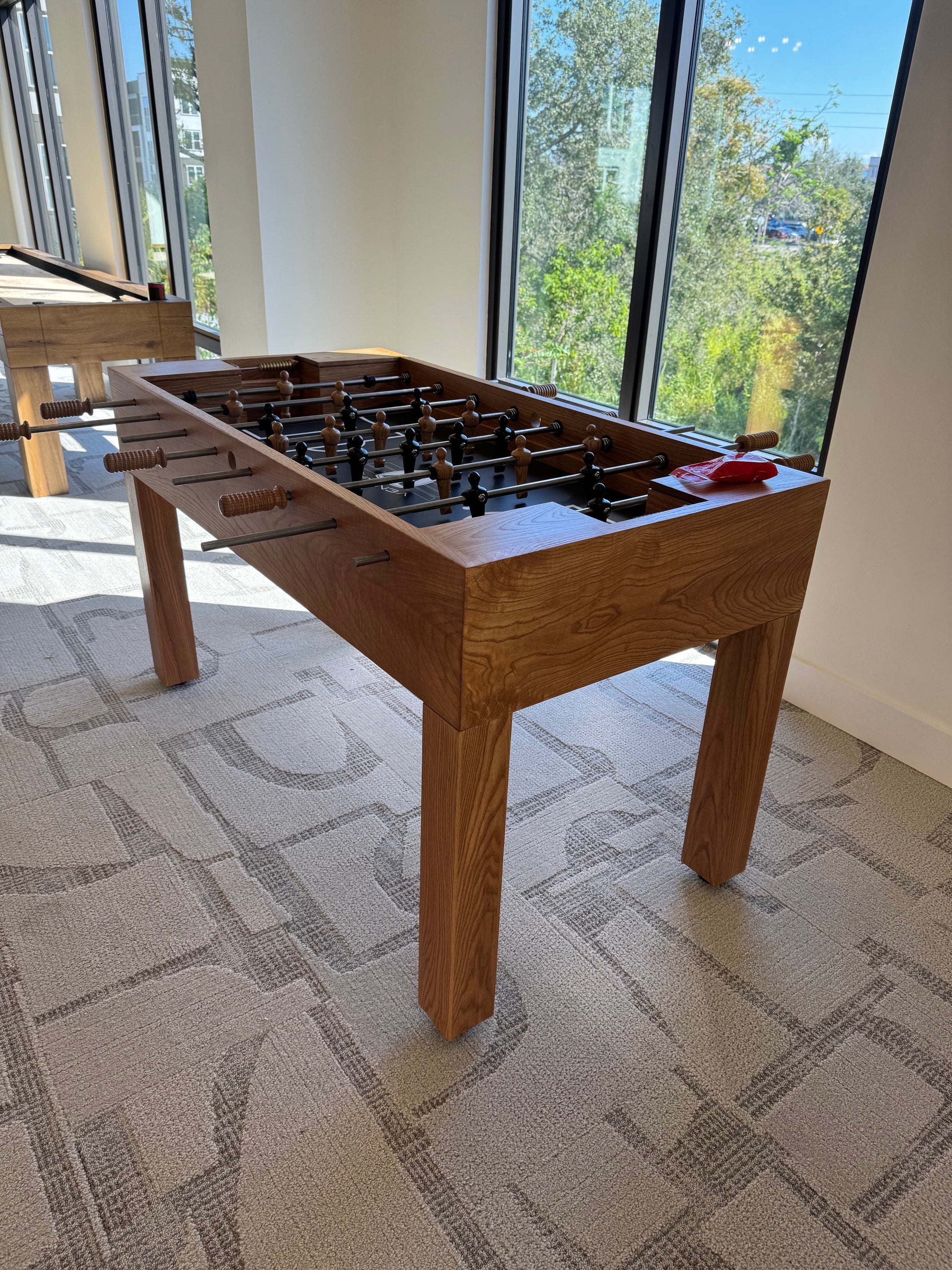 Wooden Venture table with a modern interior design featuring large windows and patterned wallpaper.