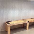 A Champion 12' Richland Shuffleboard Table stands against a light gray patterned wall indoors.