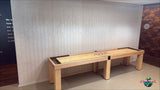 A Champion 12' Richland Shuffleboard Table stands against a light gray patterned wall indoors.