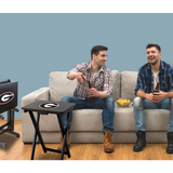 Two men sitting on a couch with a sports-themed side table.