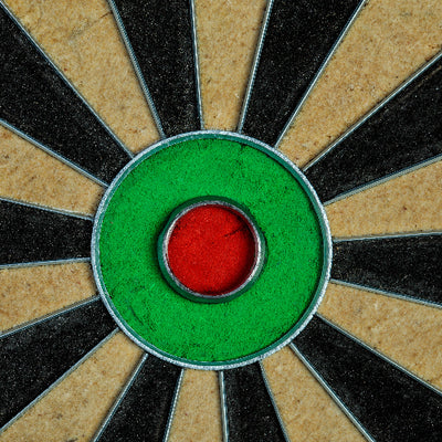 Close-up of a dartboard with concentric circles in green, red, and black.