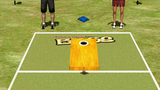 Incredible Technologies Arcade Collection Kit beside cornhole on grass, two players’ legs visible.