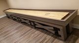 The Champion Rustic 9' Shuffleboard Table by Champion stands on a wood floor near a beige wall.