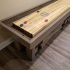 Champion Rustic 9' Shuffleboard Table by Champion with blue and red pucks on maple playfield.