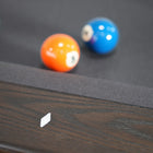 Three balls rest on a Nixon KAI 7' Slate Pool Table in Waxed Brown by Nixon Billiards.