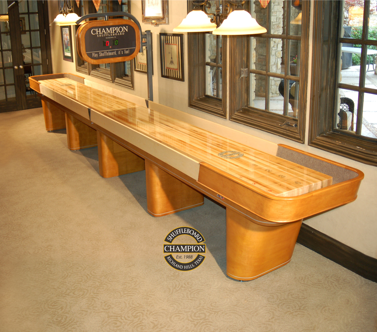 A Champion Capri 9' Shuffleboard Table sits in a carpeted game room as modern furniture.