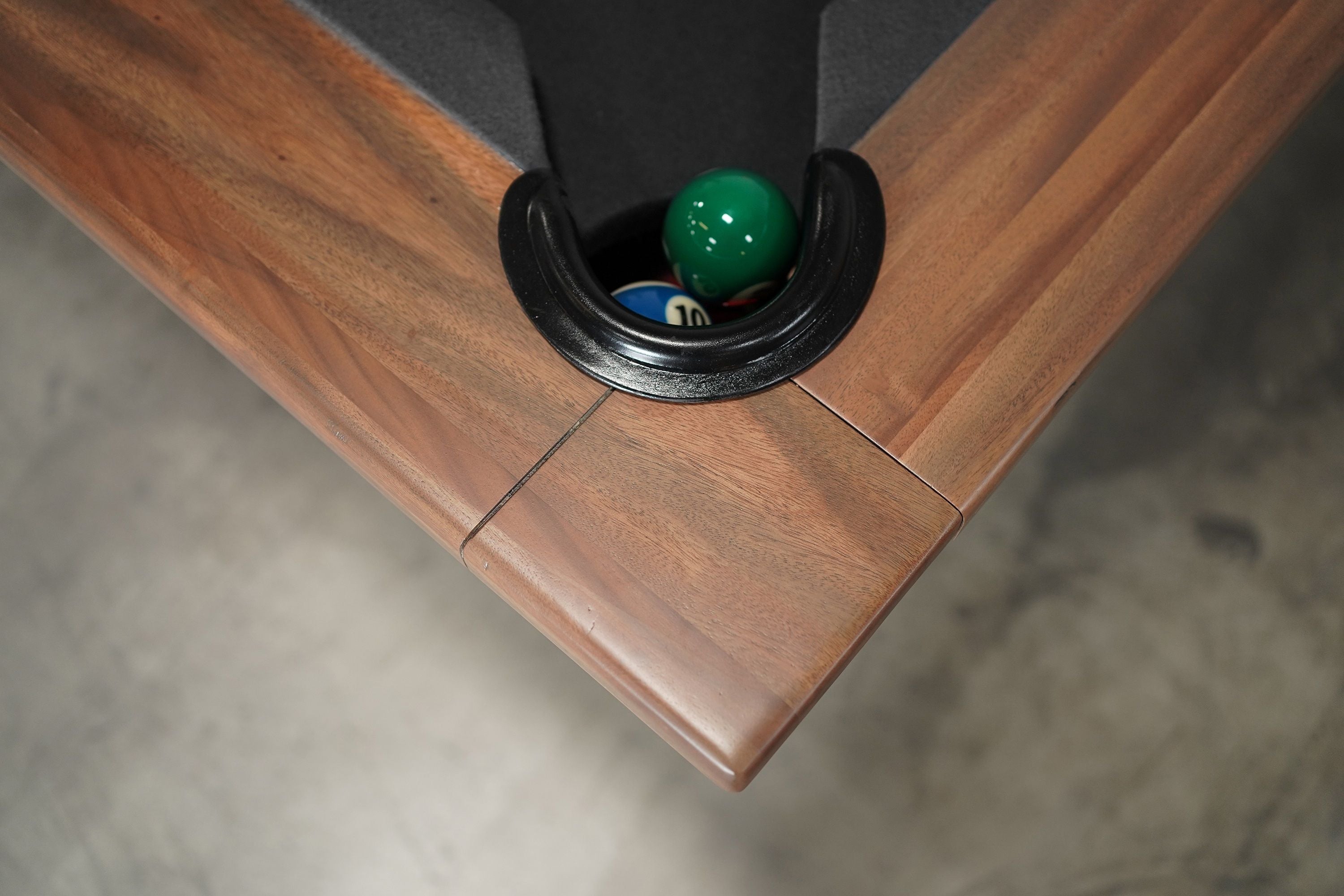 Walnut Nixon KAI 7' Pool Table by Nixon Billiards with pool balls in the corner pocket.