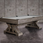 The Nixon Jasper 7' Slate Pool Table by Nixon Billiards sits on a concrete floor, gray felt top.