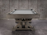 The Nixon Jasper 8' Slate Pool Table by Nixon Billiards in Weathered Slate sits before a concrete wall.