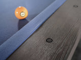 A yellow 9-ball sits on a Nixon Kemp 8' Slate Pool Table by Nixon Billiards in Grayson Grey.