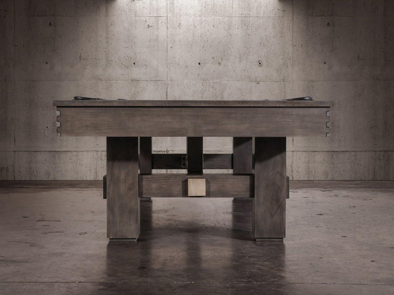The Nixon Kemp 8' Slate Pool Table by Nixon Billiards adds charm to the modern concrete room.