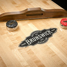 Brunswick Billiards Parsons 12' Shuffleboard Table with wooden scorer and red/black pucks.