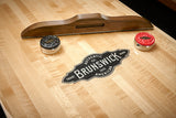 Brunswick Billiards Parsons 12' Shuffleboard Table with wooden scorer and red/black pucks.