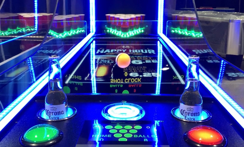 Valley Jet-Pong game by Valley with neon lights, two Corona bottles, and plastic cups behind.