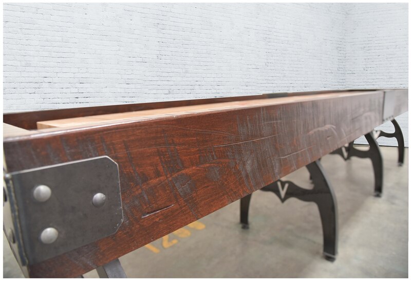 Venture Williamsburg 12' Shuffleboard Table by Venture with metal legs against a white brick wall.