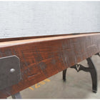 Venture Williamsburg 12' Shuffleboard Table by Venture with metal legs against a white brick wall.