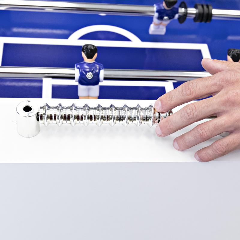 A hand grips the handle of an American Legend Manhattan Foosball Table with blue and white players.