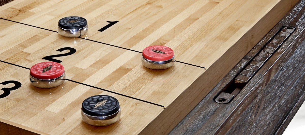 Close-up of Brunswick Billiards Canton 14' Shuffleboard Table in Black Forest with pucks.