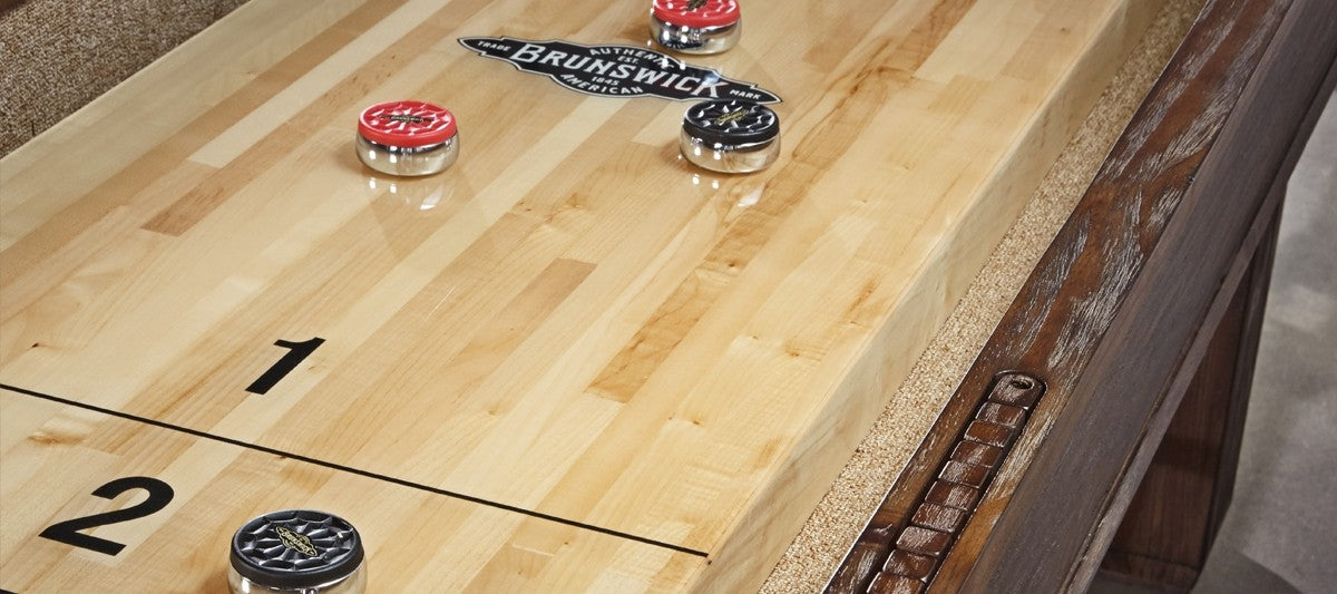 Brunswick Billiards Canton 14' Shuffleboard Table in Black Forest with red and black pucks.
