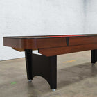 A Venture Classic Bank Shot 9' Shuffleboard Table with black legs stands on a concrete floor.
