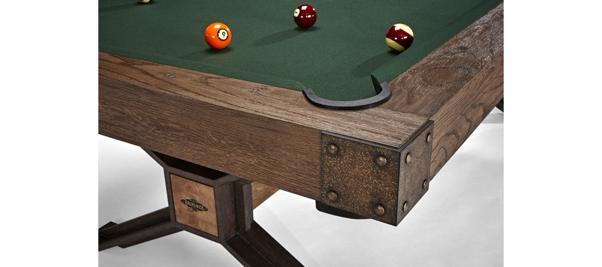 Corner of a Brunswick Billiards Dameron 8' Slate Pool Table in Nutmeg with four balls on felt.