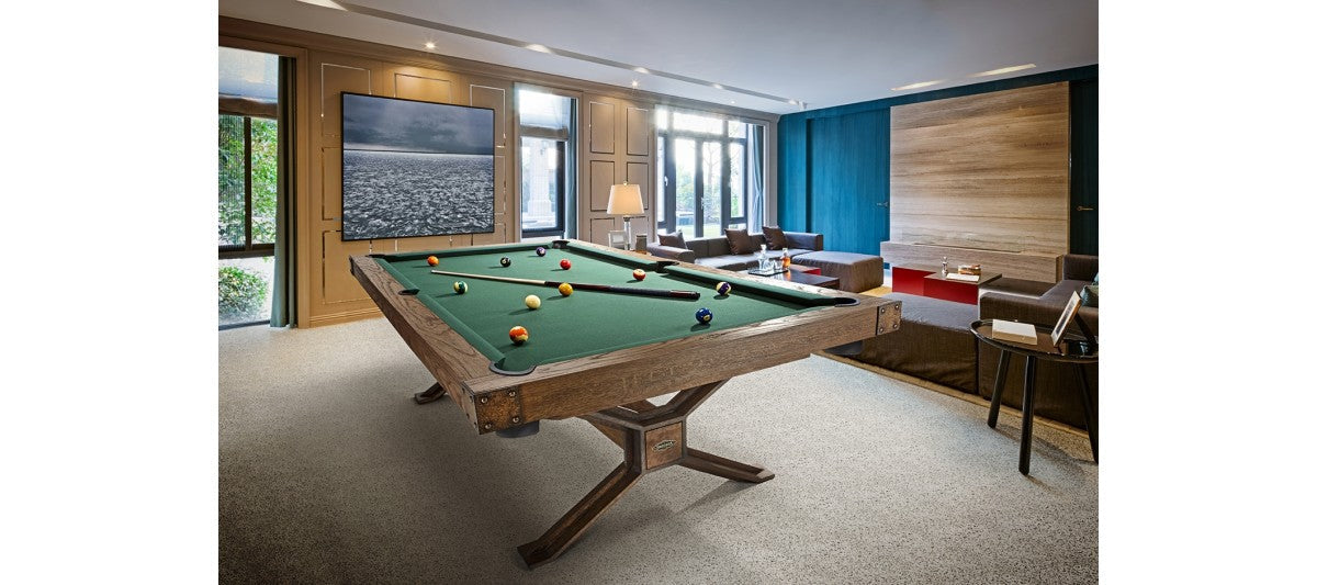 A Brunswick Billiards Dameron 8' Slate Pool Table in Nutmeg in a modern room with large windows.