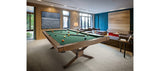 A Brunswick Billiards Dameron 8' Slate Pool Table in Nutmeg in a modern room with large windows.
