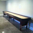 The Champion 9' The Grand Champion Shuffleboard Table stands against a blank wall on polished floors.