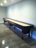The Champion 9' The Grand Champion Shuffleboard Table stands against a blank wall on polished floors.
