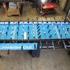 Warrior 8 Players Foosball Table with split bearing in a workshop filled with tools.
