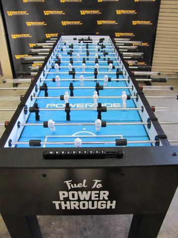 Warrior 8 Players Foosball Table with split bearing, in front of a Warrior backdrop.