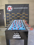 A Warrior 8 Players Foosball Table sits before a branded Warrior Table Soccer banner.