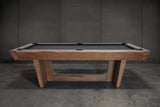 Nixon KAI 8' Slate Pool Table in Walnut by Nixon Billiards, shown with dark felt and gray wall.