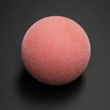 A red Warrior foosball ball from the set of 4 on a dark, flat surface.