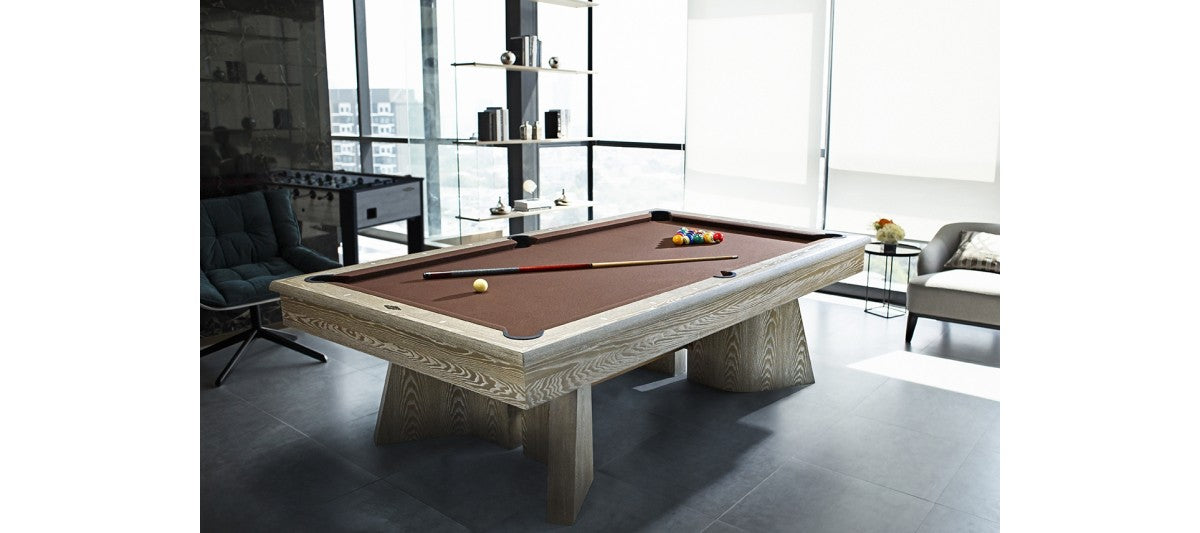 A modern room with a Brunswick Billiards Sagrada 8' Slate Pool Table in Sandwashed and cue stick.