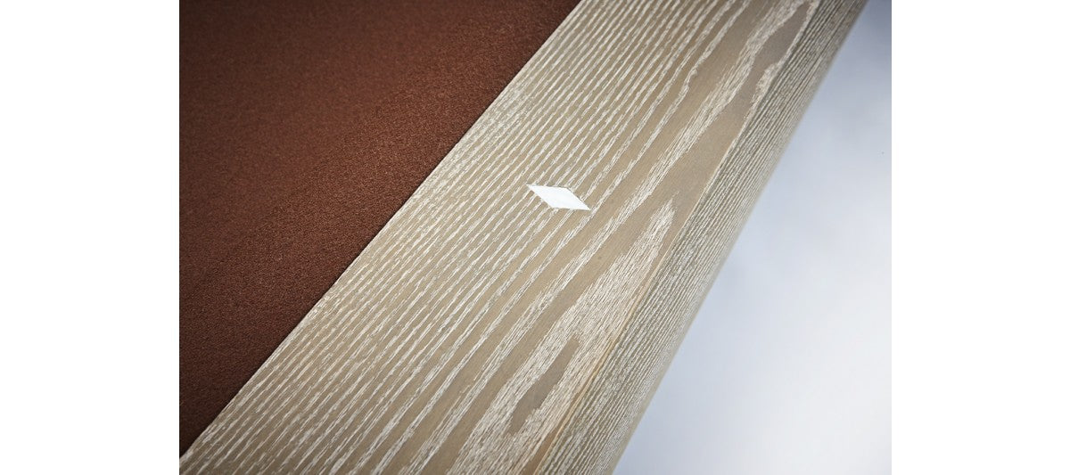 A white diamond sticker on sandwashed wood near a Brunswick Billiards Sagrada 8' pool table.