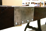 A metal plate with four bolts is fixed to the Venture Williamsburg 12' Shuffleboard Table.