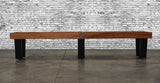 The Venture Monaco 18' Shuffleboard Table by Venture stands against a white brick wall on concrete.